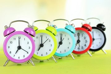 Colorful alarm clocks on table on light background