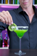 Portrait of handsome barman preparing cocktail, at bar