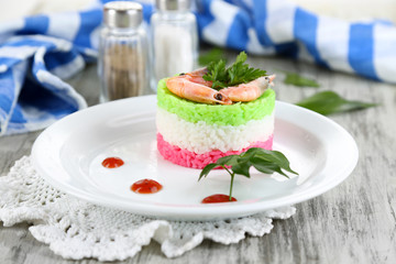 Colored rice on plate near napkin on  wooden table