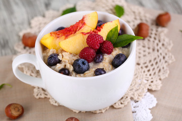 Oatmeal in cup with berries on napkins on wooden table