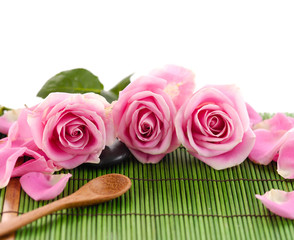 Pink rose with stones and spoon on green mat