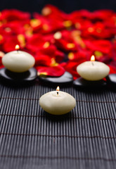 Three candle and rose petals on mat