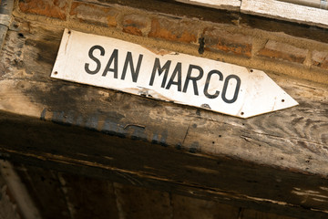 Directional sign to San Marco square on old Venetian building