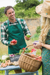 Young handsome farmer selling organic vegetables to pretty blond