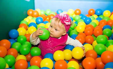 Obraz na płótnie Canvas Happy child girl in colored ball on playground