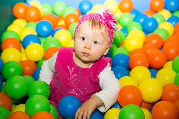 Fototapeta na wymiar Happy child girl in colored ball on playground