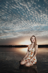 Obraz premium beautiful blond girl with dres on water