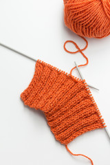Incomplete knitting project with ball of orange wool