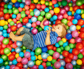 Happy child playing with colorful plastic balls