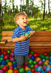 Happy child playing with colorful plastic balls