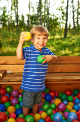 Happy child playing with colorful plastic balls