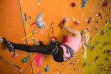 young girl climbs the steep wall on climbing gym