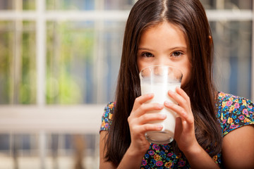 Gorgeous little girl drinking a glass of milk at home