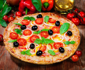 Tasty pizza and fresh ingredients on the table