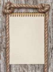 Rope, paper spiral notebook and wood background