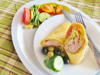 A turkey wrap with cucumbers and olives and a side salad