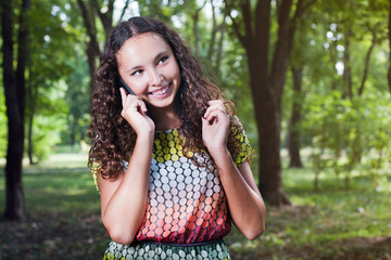 Fototapeta premium Smiling teenage girl talking mobile outdoor