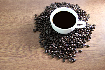 White coffee cup resting on coffee beans.