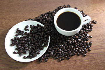 White coffee cup resting on coffee beans.