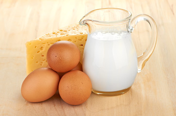 Big piece of cheese, glass jug with milk