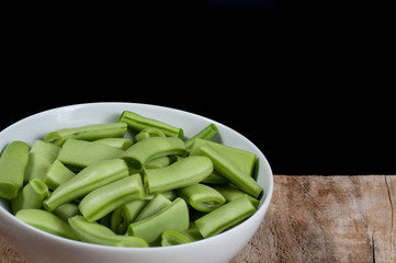 Green beans on a bowl on wooden background