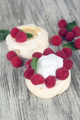 Tasty meringue cakes with berries on wooden table