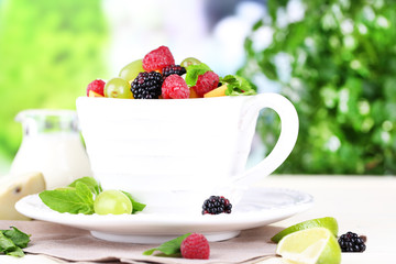 Fruit salad in cup on wooden table on nature background