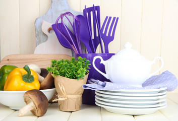 Plastic kitchen utensils in cup on wooden table