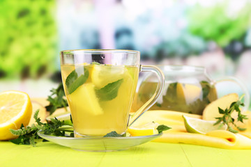 Cup of tea with ginger on wooden table on nature background