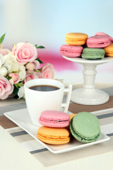Coffee and macaroons on table on light background