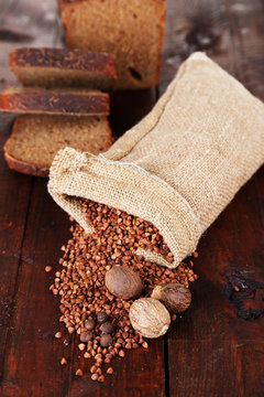 Cloth bag with buckwheat groats and spices on wooden background