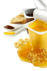Tasty desserts in open plastic cups and honey combs, isolated
