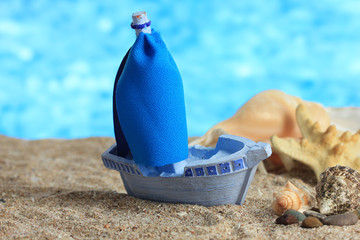 Blue toy ship on sand, on blue background