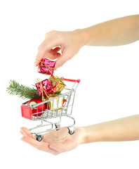 Hand holding Christmas gifts in shopping trolley, isolated