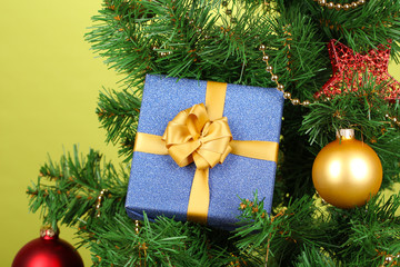 Gift on Christmas tree on color background