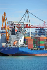 Container stack and cargo ship under crane bridge