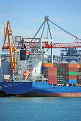 Fototapeta premium Container stack and cargo ship under crane bridge