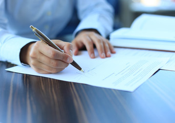 Businesswoman sitting at office desk signing a contract