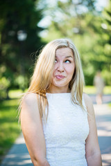 Naklejka premium Beautiful young blond woman in a white dress outdoors