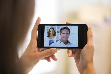 Closeup of a female hand holding a smartphone during a skype vid
