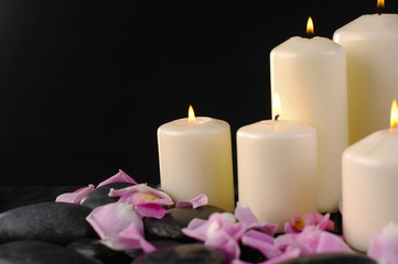White candle and rose petals and stones