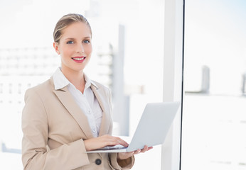 Smiling blonde businesswoman using laptop