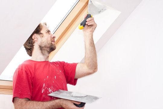 Manual worker with wall plastering tools inside a house