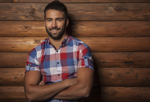 Portrait of young beautiful man against wooden wall.