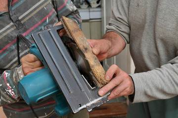 Home renovation worker adjust electric saw for parquet cutting