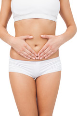 Fototapeta premium Slim young woman touching her belly with her hands