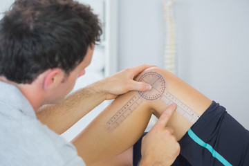 Physiotherapist checking knee with goniometer - obrazy, fototapety, plakaty