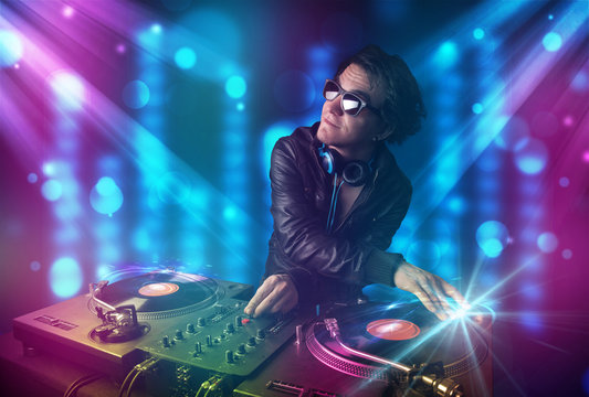 Dj mixing music in a club with blue and purple lights