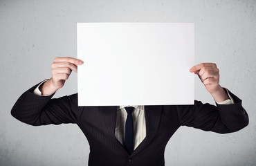 Businessman holding in front of his head a paper with copy space