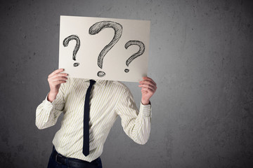 Businessman holding a paper with question marks in front of his